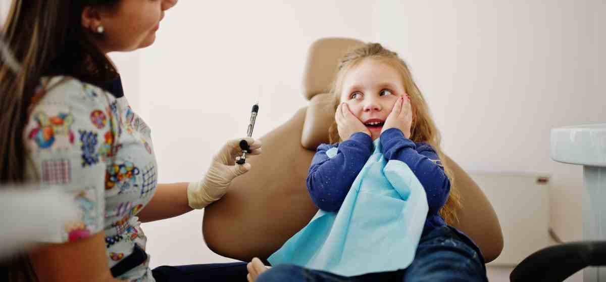 Nervous young girl in a dental chair being reassured by dentist that she has nothing to worry about